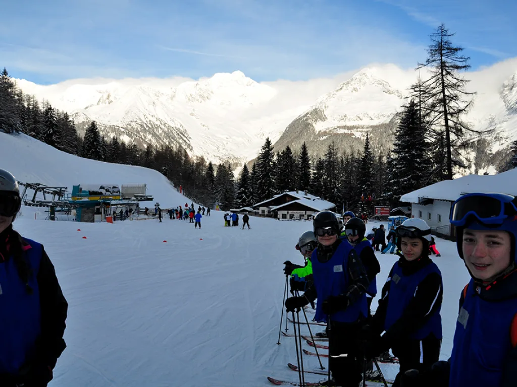 Skigruppe sammelt sich an der Talstation vor der Bergkulisse.